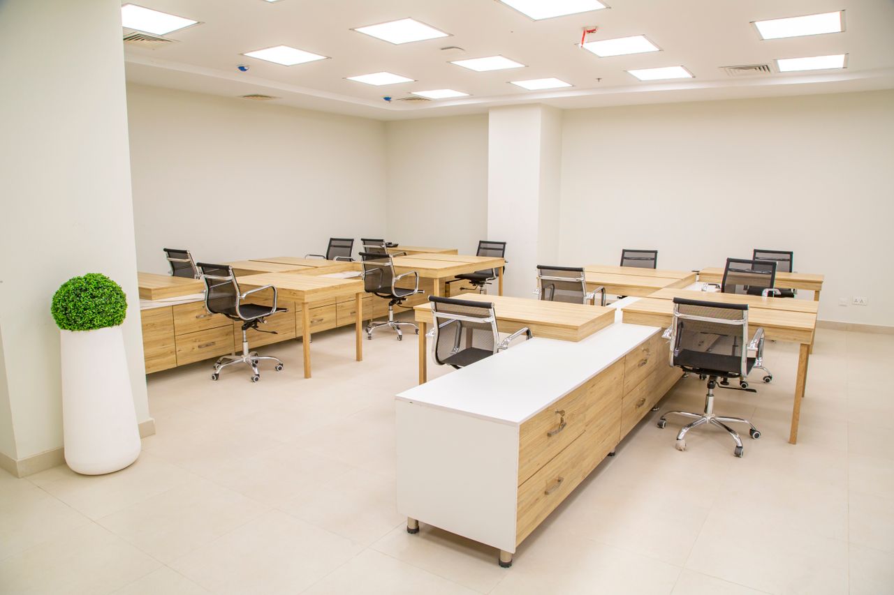 gallery-04 A bright, modern office space featuring wooden desks, rolling chairs, and ample lighting.