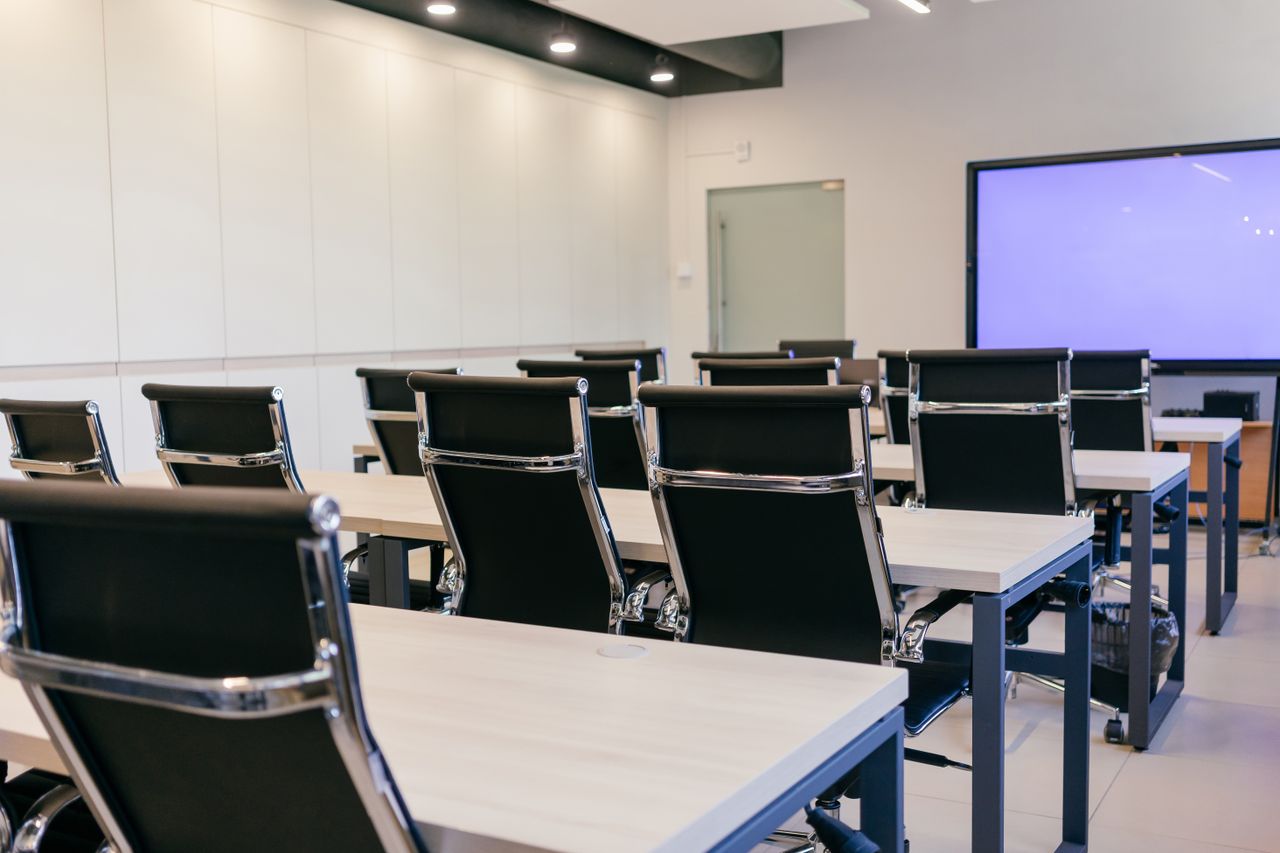 gallery-02 Spacious, modern conference room with black chairs and a projection screen.